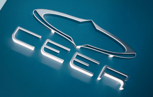 The image shows the illuminated logo of Ceer, featuring a stylized outline of a star shape above the bold, uppercase letters CEER on a blue background, symbolizing Ceer’s commitment to Driving The Future.